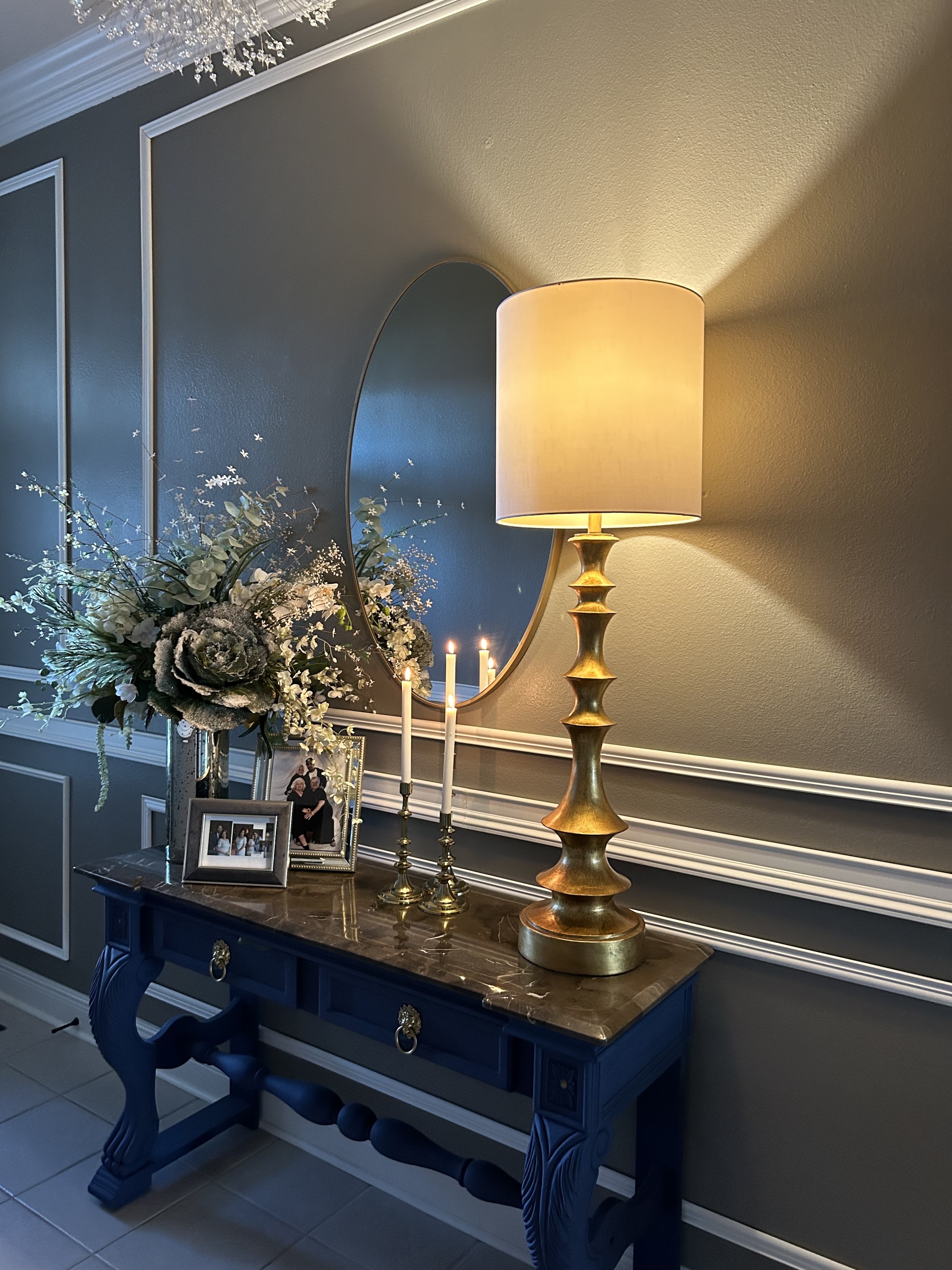 Olivier Design Co styled entryway — an oval mirror, brass lamp, and fresh florals arranged on a console table